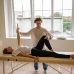 A specialist performs therapy on a woman lying on a massage table in a modern clinic setting.